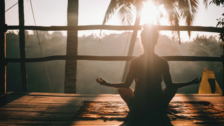 Woman sitting quietly on a wooden deck, phone-free, in morning light