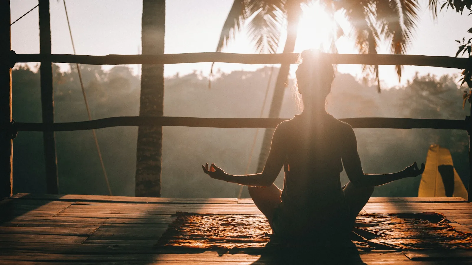 Woman sitting quietly on a wooden deck, phone-free, in morning light