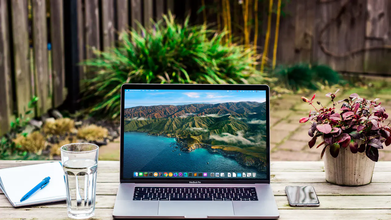 Laptop on a wooden table beside a glass of water
