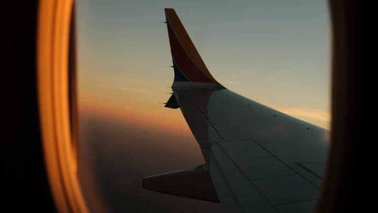 Aeroplane wing at sunset seen through a cabin window