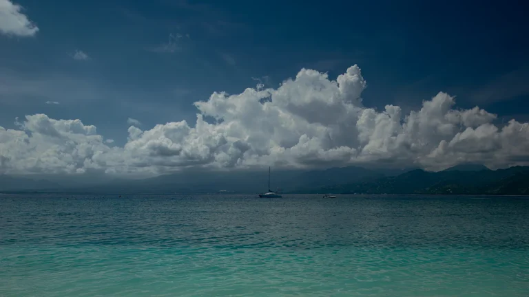 Sandy beach with clear blue water under a partly cloudy sky