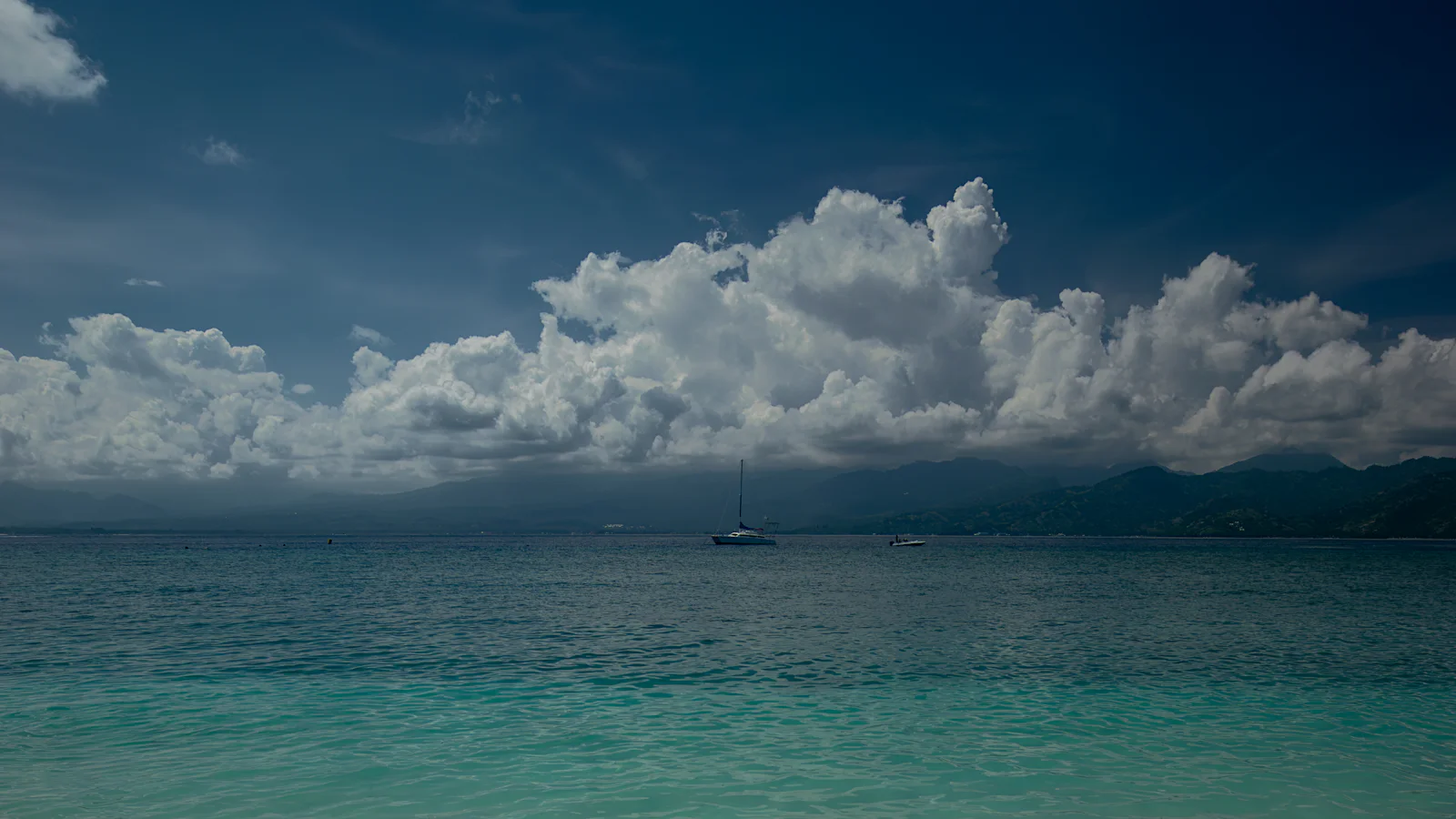 Sandy beach with clear blue water under a partly cloudy sky