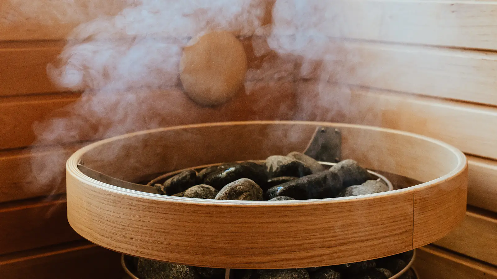 Steam rising from hot stones in a wooden sauna heater