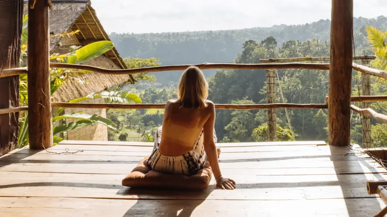 Woman sitting on a wooden porch in a tropical setting