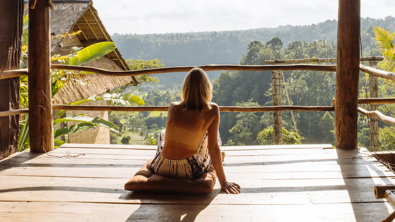 Woman sitting on a wooden porch in a tropical setting