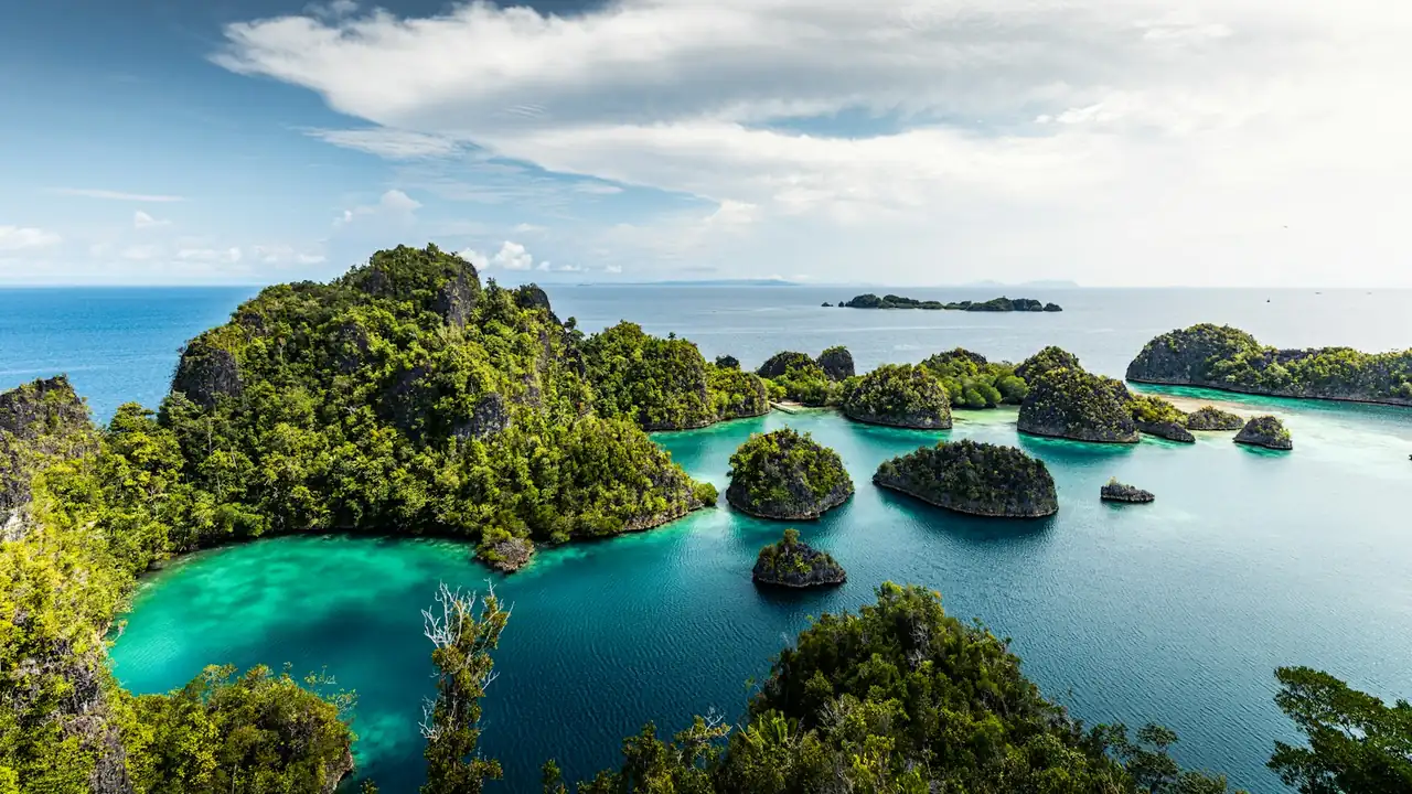 Group of small green islands in turquoise water at Raja Ampat